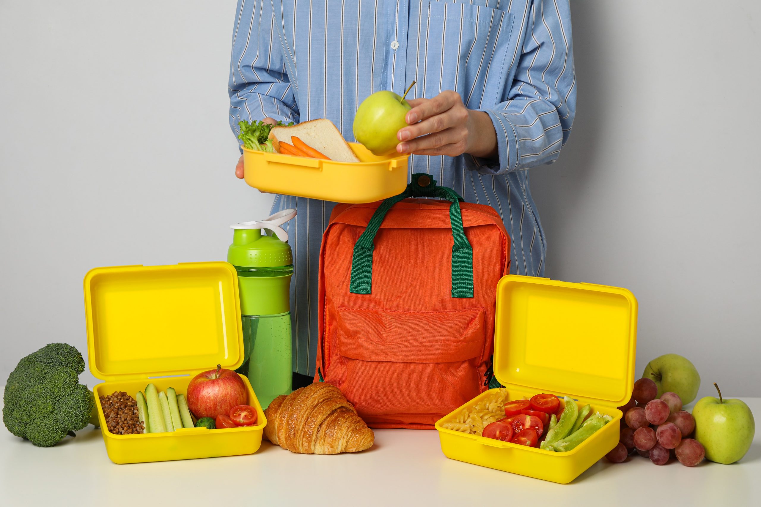 Lunch boxes with food and a school backpack