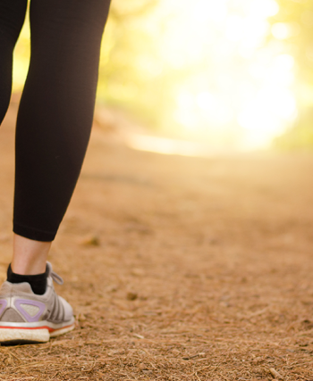 Sabah güneşi altında parkta yürüyen bir kişi, doğayla iç içe sakin bir yürüyüş yapıyor.