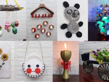 Renkli cam şişeler, karton kutular ve kumaş parçaları gibi atık malzemelerle hazırlanmış el yapımı dekoratif objelerin ahşap bir masa üzerinde sergilendiği görüntü.