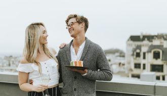 Bir çift birlikte masa başında not alıyor ve plan yapıyor; birbirlerine bakarak gülümsüyor ve ortak hedefler üzerinde konuşuyorlar.