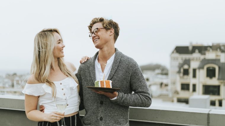 Bir çift birlikte masa başında not alıyor ve plan yapıyor; birbirlerine bakarak gülümsüyor ve ortak hedefler üzerinde konuşuyorlar.