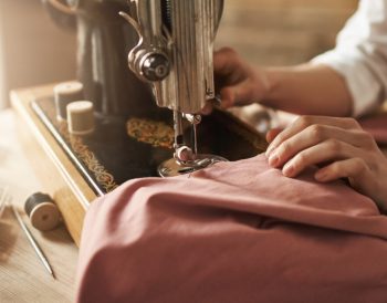 Dikiş makinesi kullanmadan, iğne ve iplik ile basit bir elbise hazırlama sürecini gösteren çalışma masası ve malzemeler.