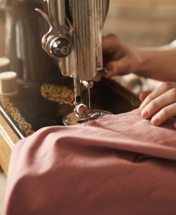 Dikiş makinesi kullanmadan, iğne ve iplik ile basit bir elbise hazırlama sürecini gösteren çalışma masası ve malzemeler.