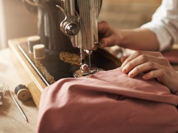 Dikiş makinesi kullanmadan, iğne ve iplik ile basit bir elbise hazırlama sürecini gösteren çalışma masası ve malzemeler.