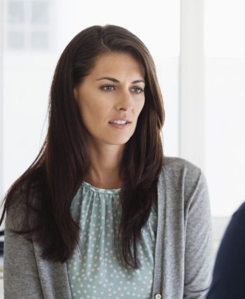 Karşısındaki kişiye konuşurken tereddütle bakan, dudakları arasından “hayır” demeye çalışan bir kişinin düşünceli şekilde ellerini birleştirdiği anın görüldüğü, arka planı flu bir iç mekân sahnesi.