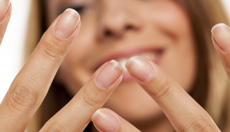 Badem, yumurta, avokado, yeşil yapraklı sebzeler ve su bardağının yer aldığı, sağlıklı tırnaklar için besleyici gıdaların bulunduğu ahşap masa düzeni.