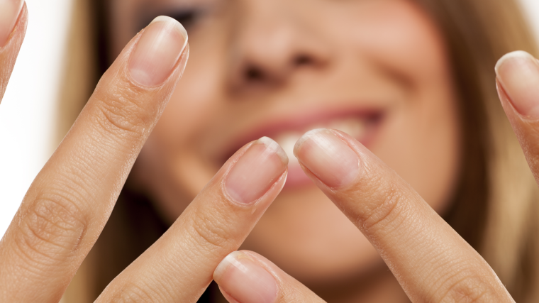 Badem, yumurta, avokado, yeşil yapraklı sebzeler ve su bardağının yer aldığı, sağlıklı tırnaklar için besleyici gıdaların bulunduğu ahşap masa düzeni.